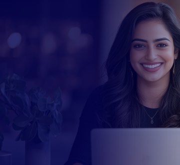 mulher de cabelos escuros sorrindo sentada com um notebook em frente