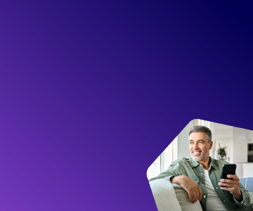 Foto de homem sentado confortavelmente, segurando seu celular em uma das m�os e sorrindo enquanto olha para o horizonte.